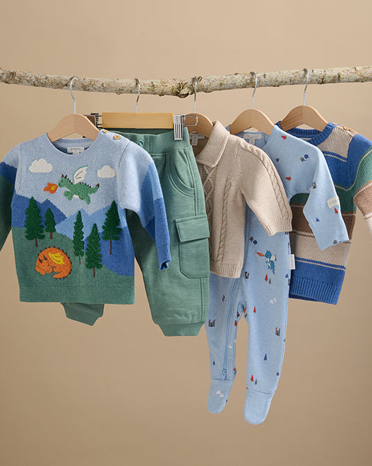 Blue and green kids clothes hanging from branch