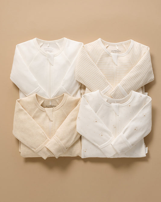 set of 4 neutral coloured baby growsuits folded